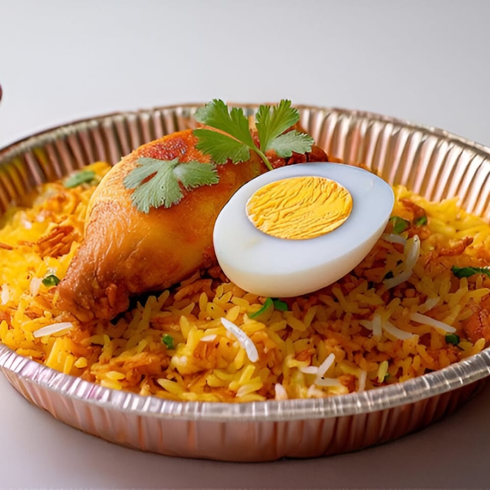 Chicken biryani with a hard-boiled egg and cilantro in a foil container from Namaste India Cafe.